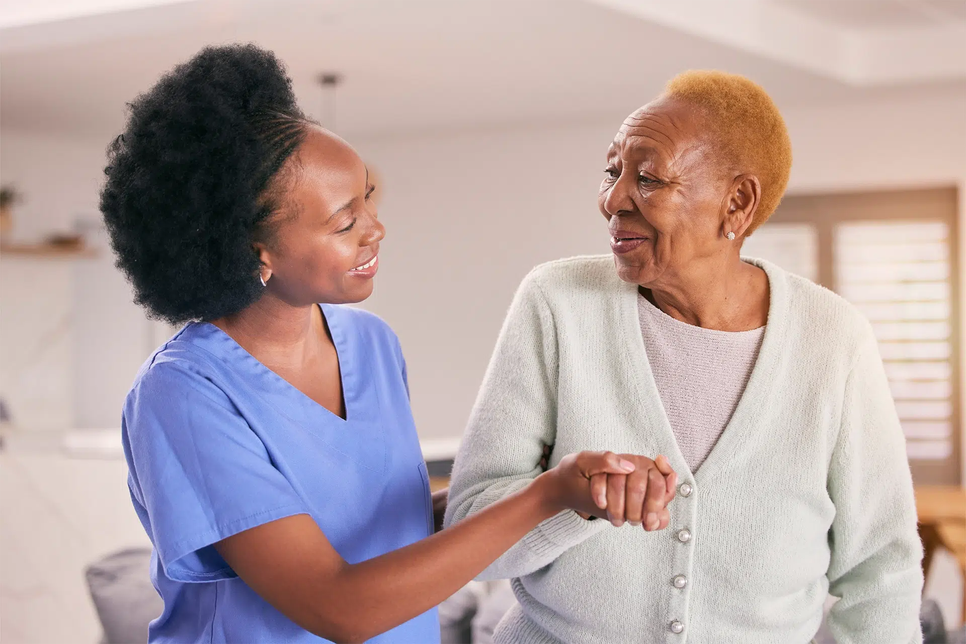 Compassionate hospice caregiver holding a patient's hand during an in-home visit, reflecting the personalized support and dignity provided by Eternal Faith Hospice.
