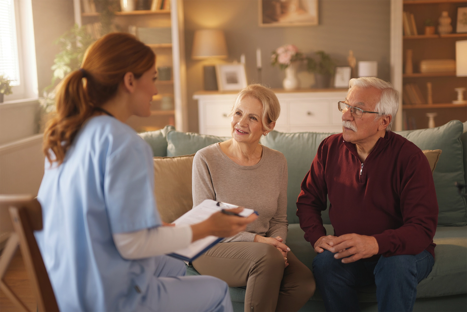 Palliative care nurse discussing symptom management and treatment options with an older couple in their home.
