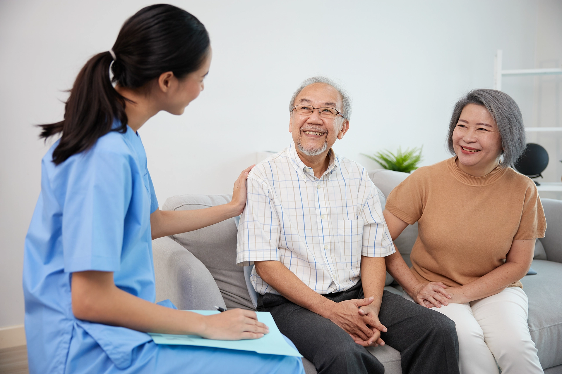 Palliative care nurse meeting with an older couple at home to discuss symptom management, treatment goals, and ongoing support.